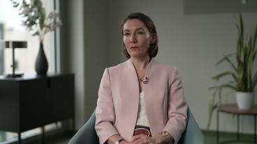 Eine mittelalte, Weiße Frau in lachsfarbenem Jackett sitzt in einem Büro. Es ist Politikwissenschaftlerin Claudia Major.