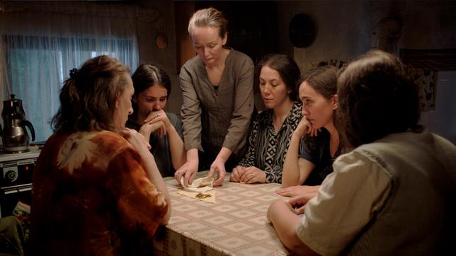 Eine Gruppe an Frauen sitzen um einen Küchentisch.