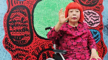 Bild: picture alliance / dpa | Katsuki Awaya Yayoi Kusama hebt die Hand und winkt.