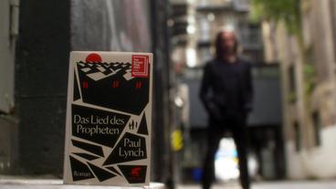 Das Buch "Das Lied des Propheten" auf dem Boden stehend.