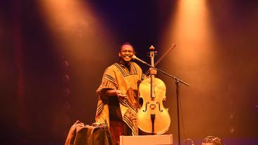 Abel Selaocoe auf der Bühne, er lacht und hält sein Cello in der Hand.