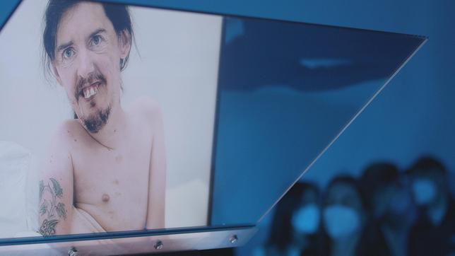 Ein Filmscreening zeigt einen Mann mit heller Haut und Tatoos
