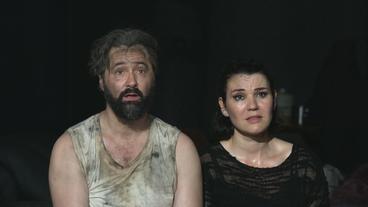 Zwei dreckbeschmierte Menschen auf einer Theaterbühen