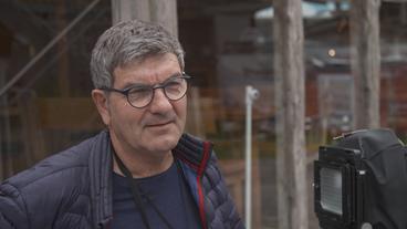 Ein mittelalter weißer Mann gibt ein Interview, neben ihm eine Kamera