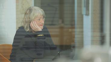 Bild: BR Eine Frau mit weißen Haaren stit allein im Café