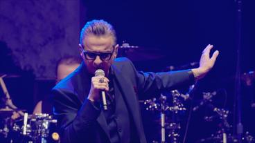 Bild: Columbia Records Ein Mann mit schwarzem Anzug und Sonnebrille auf einer Konzertbühne