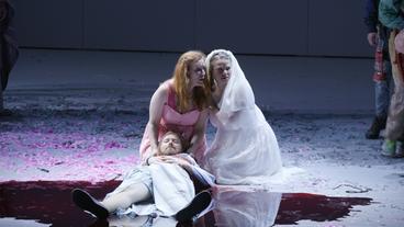 Toter Mann und zwei trauernde Frauen auf einer Theaterbühne