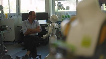 Ein Mann sitzt neben einem Roboter
