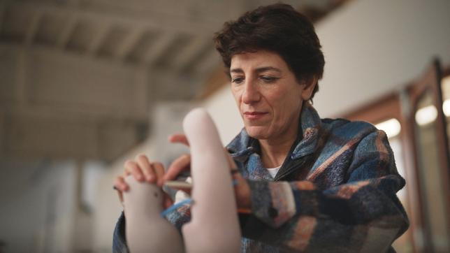 Eine Frau mit kurzen, dunklen Haaren formt eine Skulptur mir ihren Händen