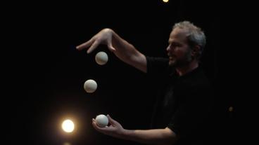 Ein Mann jongliert mit weißen Bällen