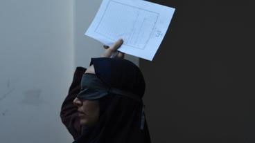 Eine verschleierte Frau hält ein Bild in die Luft
