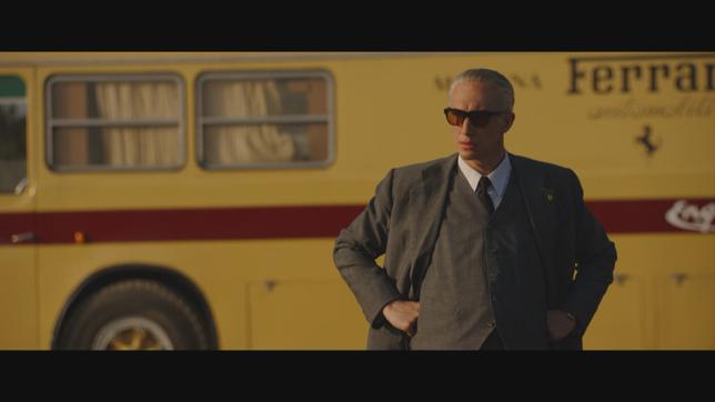Ein Mann steht mit Sonnenbrille vor einem gelben Bus