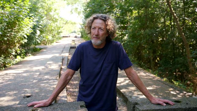 Bild: ARD/ttt Ein Mann mit Lockenkopf steht auf einem Waldweg