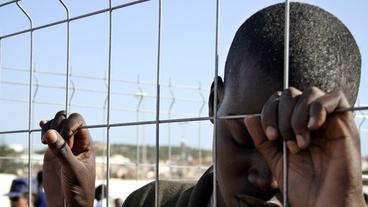 Bild: AFP PHOTO/Melmoth Flüchtlinge sitzen auf dem Grenzzaun von Melilla