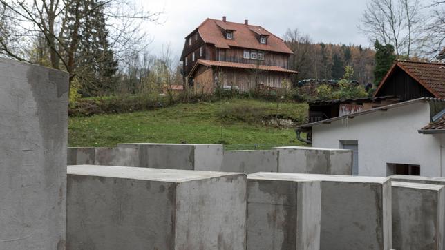 Mehrere graue Beton-Stelen vor einem Haus.