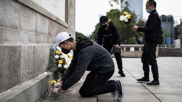 Bild: laif/Wang He Menschen legen Blumen an einer Gedenktafel ab