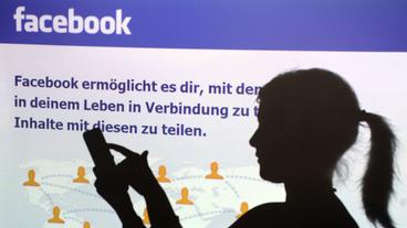 Bild: Pandora-Film Eine Frau mit Smartphone vor einer Facebook-Seite