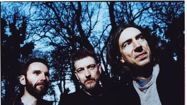 Drei Männer vor Bäumen im Schattenriss unter blauem Himmel: Snow Patrol ist zurück mit einem neuen Album.