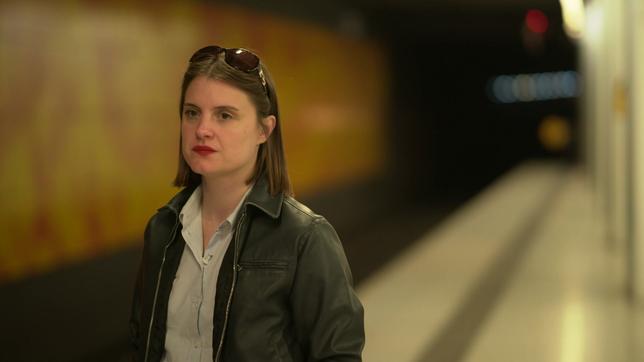 Eine junge Frau mit glatten, brünetten Haaren steht an einer U-Bahn-Haltestelle. Es ist die Sängerin Sophia Kennedy.