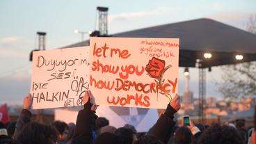Bild: NDR Ein Transparent bei einer Demonstration: "Let me show how Democracy works".