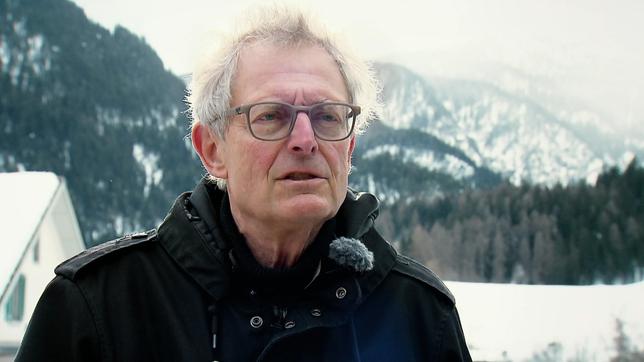 Andreas Hoessli, Filmemacher, während eines Interviews, im Hintergrund schneebedeckte Berge und Wald.