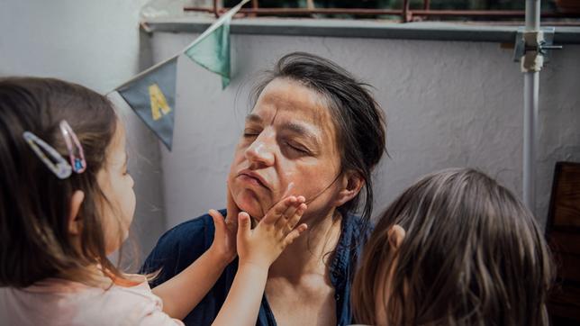 Kinder schmieren ihrer Mutter Creme ins Gesicht.