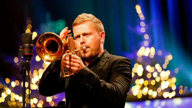 Nils Wülker spielt Trompete vor einem Mikrofon.