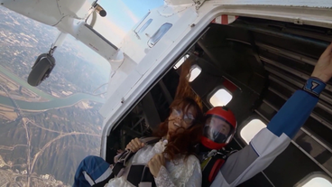 ZAZ kurz vor ihrem Fallschirmsprung. Sie ist an einen Fallschirm-Profi mit angeschnallt und sie sitzen an der offenen Luke des Flugzeugs.