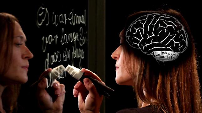 Eine Frau schreibt auf einer Glasscheibe. Auf ihrem Kopf ist das Gehirn eingeblendet.