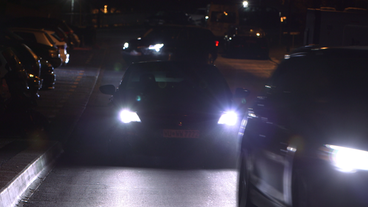 Autos mit grellen LED-Scheinwerfern fahren im Dunkeln durch Stadt