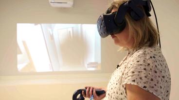 Bild: WDR Frau mit VR-Brille im Vordergrund, VR-Bild der altersbedingten Makuladegeneration im Hintergrund.