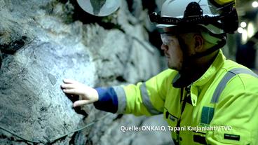 Ein Mann in Schutzkleidung vor Granitgestein.