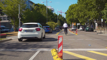 Radfahrer neben einem Autofahrer.