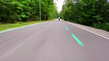 Schnurgerader und sehr breiter Fahrradweg mit Beleuchtung, mitten durch den Wald.