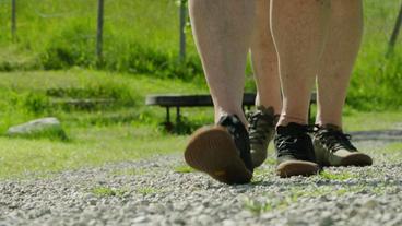 Zwei Fußpaare mit Barfußschuhen laufen auf einem Sandweg