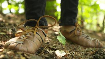 Römische Militärsandalen stehen auf Waldboden