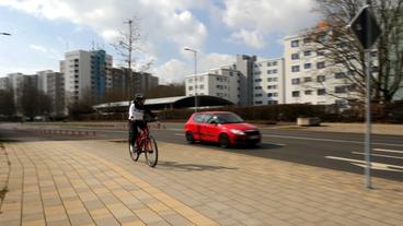 Ein Fahradfahrerin auf einem Radweg, daneben ein Auto mit viel Abstand.