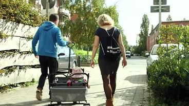 Junge Familie mit Kind und Bollerwagen auf dem Weg zum Einkaufen
