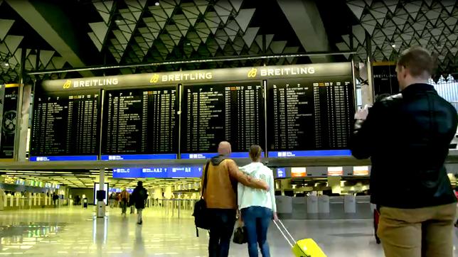 Passagiere schauen auf eine Abflugtafel im Flughafen