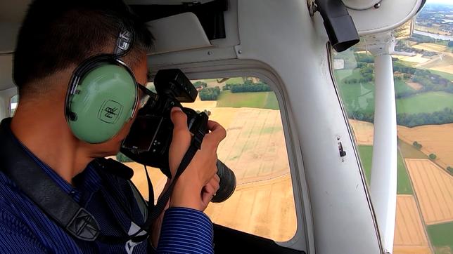 Ein Mann fotogtafiert aus einem Flugzeug heraus.