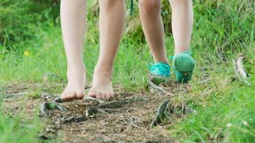 Kinderfüße laufen auf Waldboden