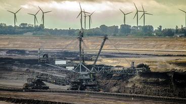 Kohleabbauhalde mit Windrädern im Hintergrund 			