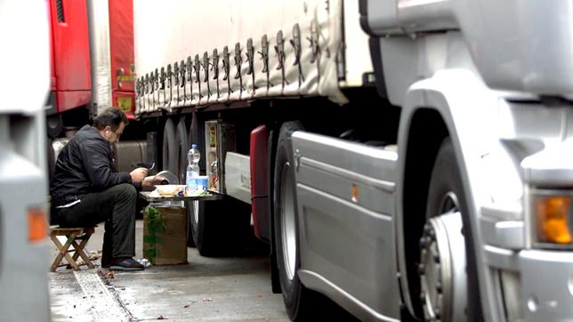 Bild: BR Lkw-Fahrer beim Abendessen zwischen Lkw auf einem Rastplatz.
