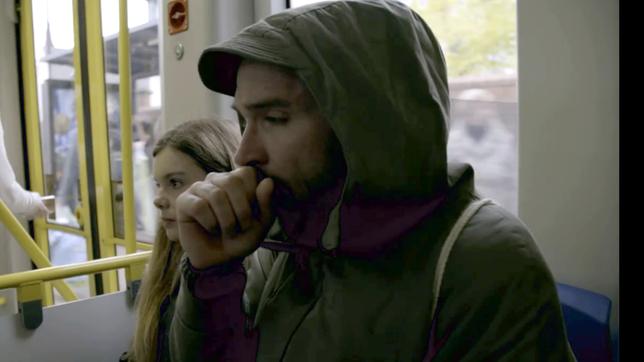 Bild: WDR Alex Sauer sitzt in der Straßenbahn neben einer jungen Frau und hustet.