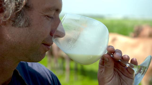 Ein Mann riecht an einem Glas Milch.