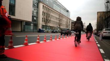 Breiter und rot gekennzeichneter Radweg auf einer Straße.