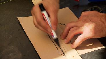Eine Hand zeichnet eine Schablone, die den Umriss eines Fußes zeigt