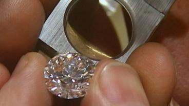 Geschliffener Diamant in den Finger eines Schleifers