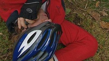Radfahrer am Boden hält sich Handy an Ohr