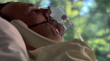 Mann mit Sauerstoffmaske in Krankenhausbett